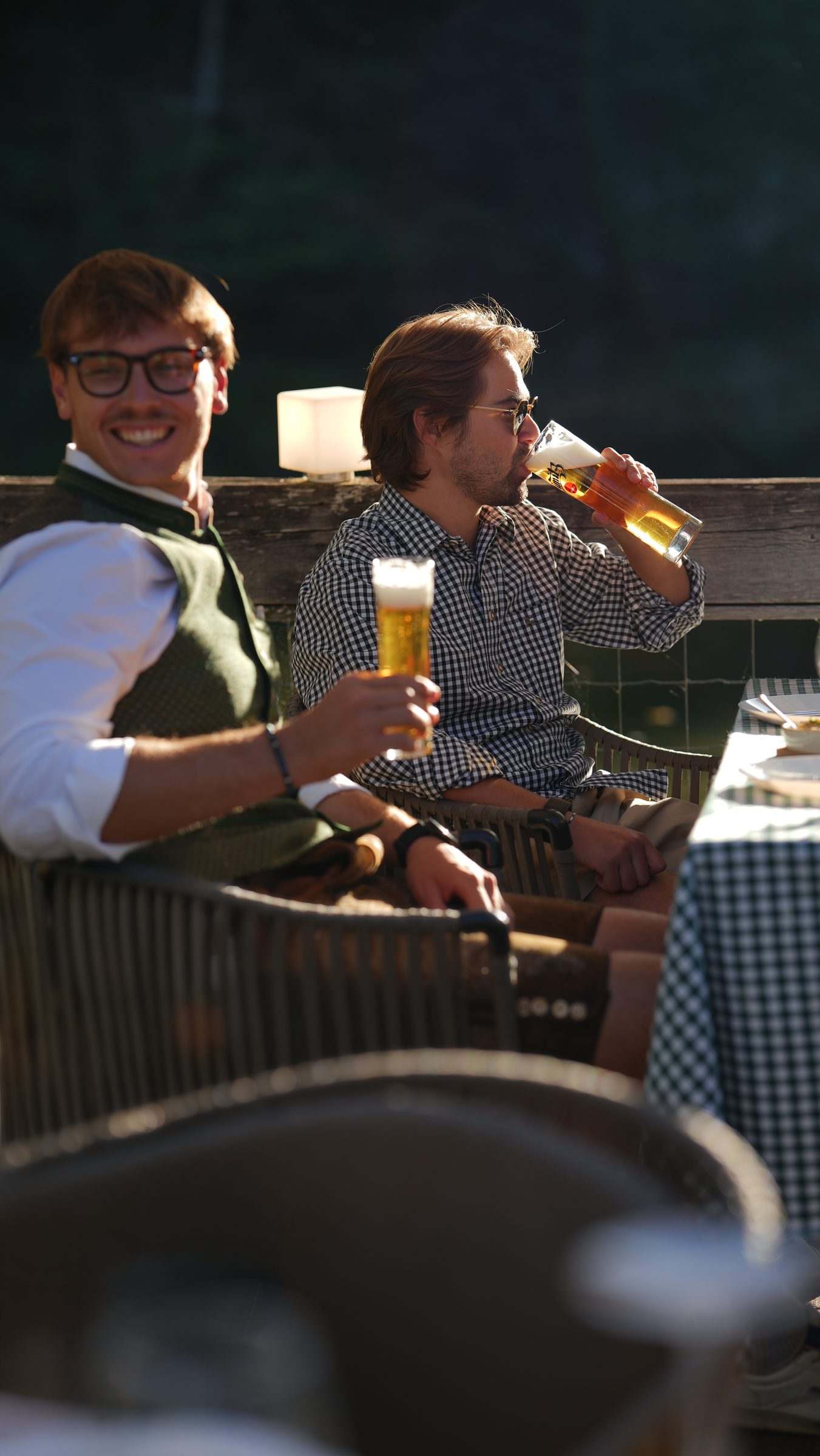 Zwei Freunde in Tracht trinken Bier auf der Terrasse