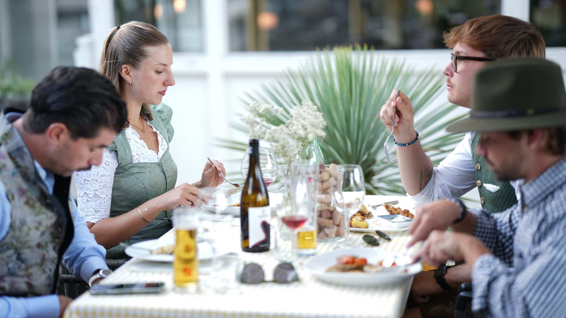 Festlich gedeckte Tafel im Freien beim Fischerwirt con amore, Gäste in Tracht essen und trinken