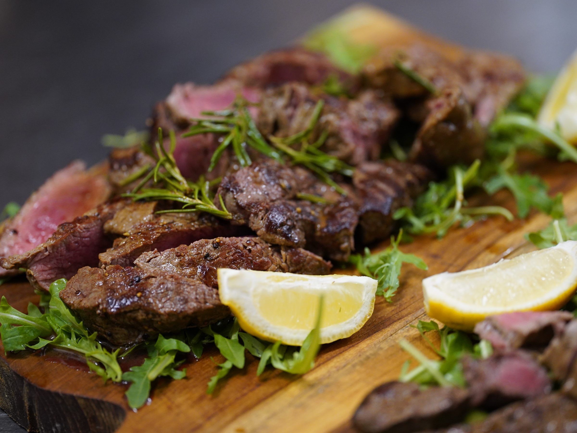 Tagliata vom Rind mit Rucola und Zitrone – auf dem Holzbrett serviert
